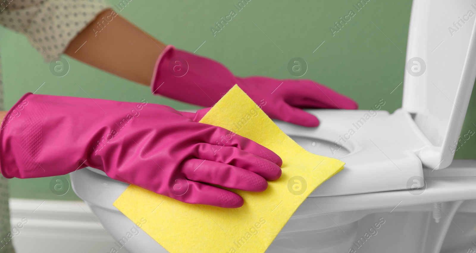 Photo of Woman cleaning toilet seat in restroom, closeup