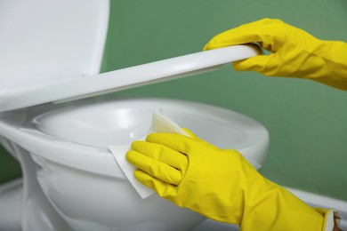 Photo of Woman cleaning toilet bowl in restroom, closeup