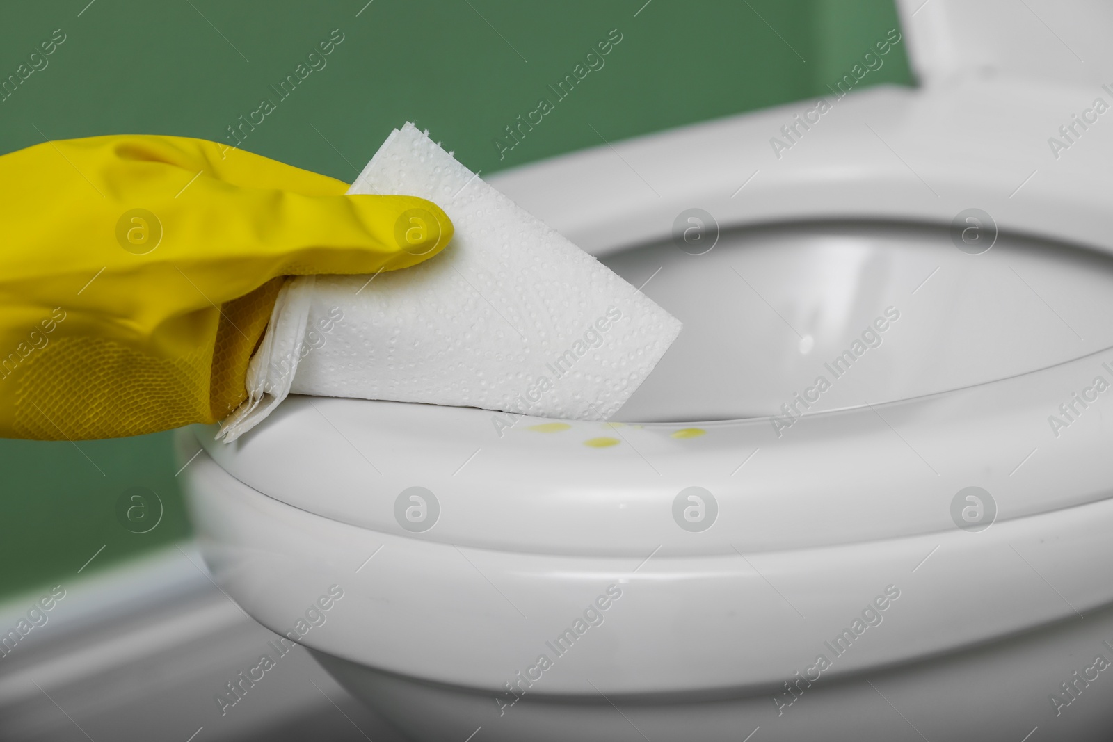 Photo of Woman wiping urine drops from toilet seat in restroom, closeup