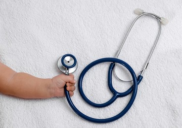 Photo of Little child with stethoscope on towel, top view. Checking baby's health