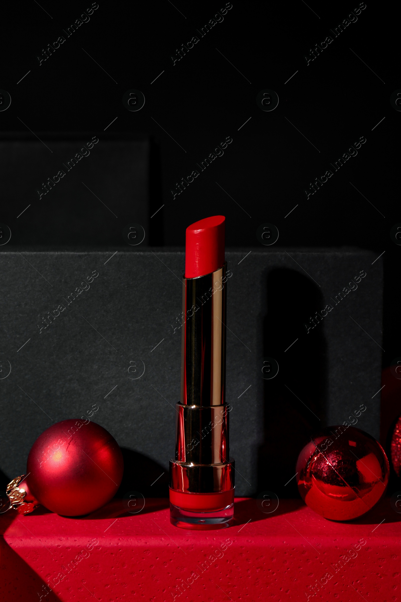 Photo of Christmas present. Red lipstick, boxes and festive decor against black background