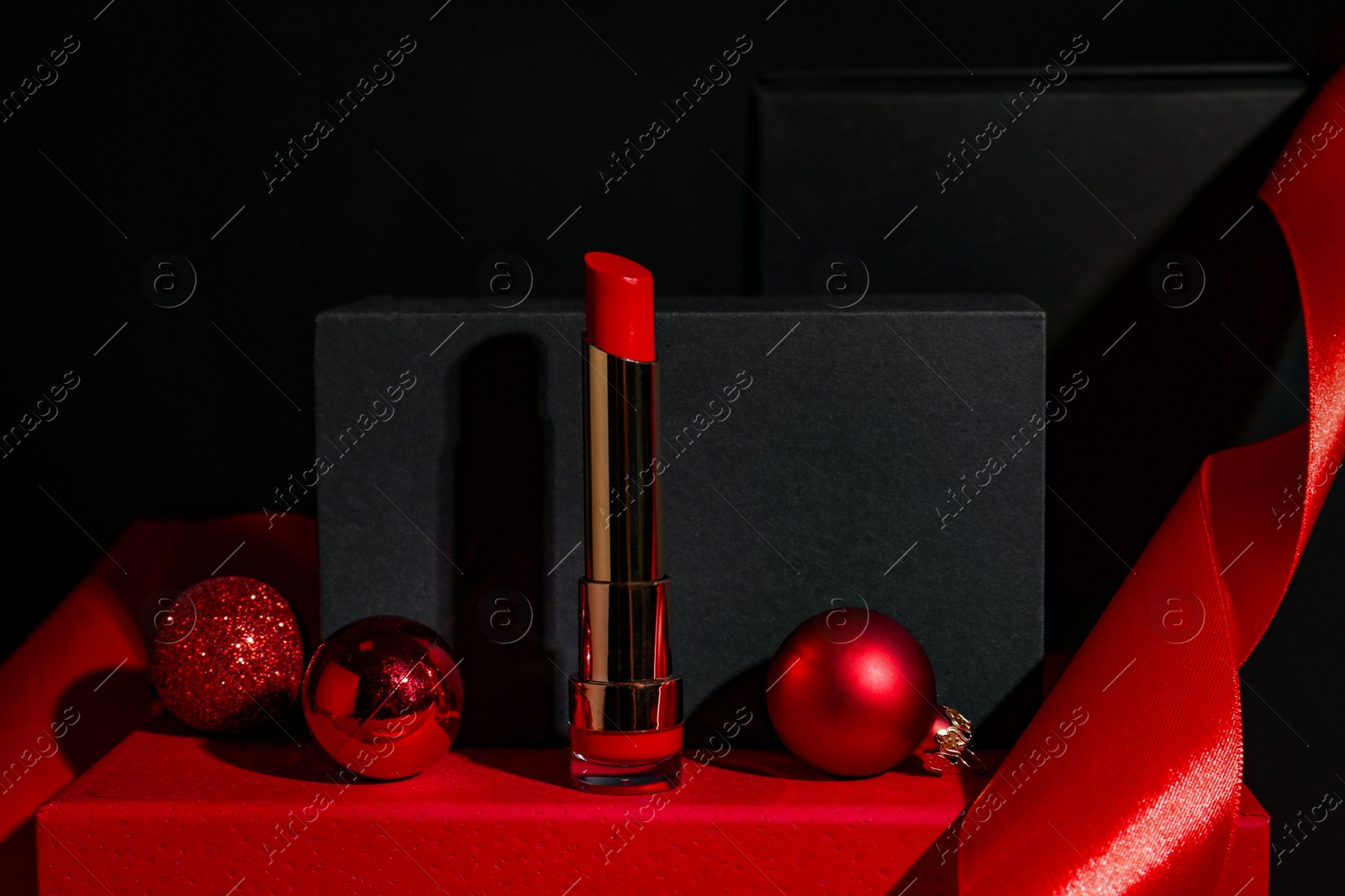 Photo of Christmas present. Red lipstick, boxes and festive decor against black background