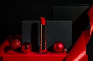 Photo of Christmas present. Red lipstick, boxes and festive decor against black background