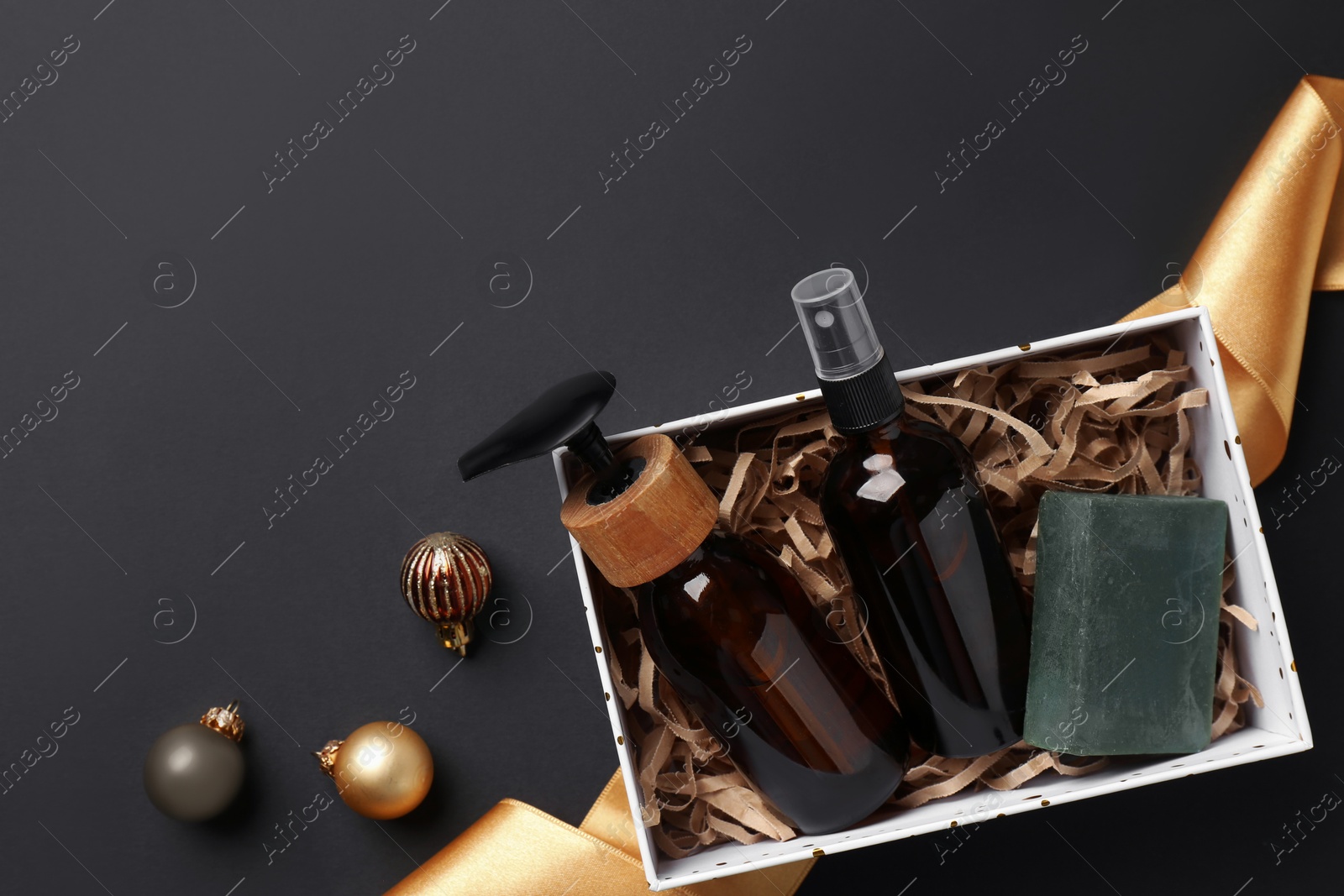 Photo of Cosmetic products in box as Christmas gift and festive decor on black background, top view. Space for text