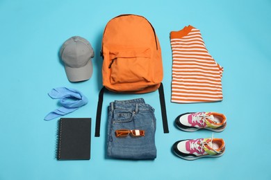 Photo of Stylish outfit with backpack on light blue background, flat lay