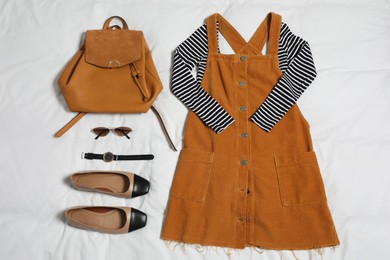 Photo of Stylish outfit with backpack on white fabric, flat lay