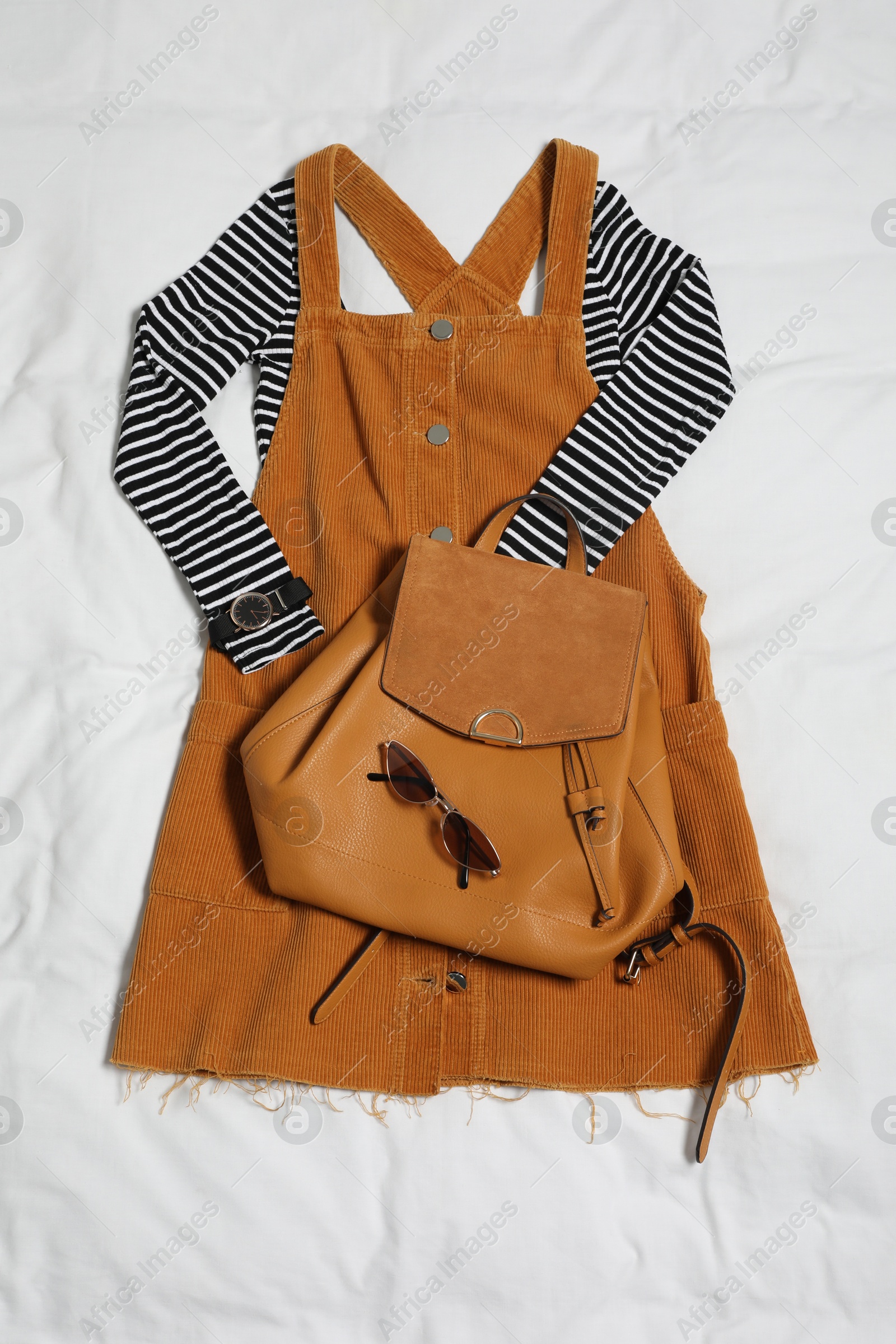 Photo of Stylish outfit with backpack on white fabric, flat lay