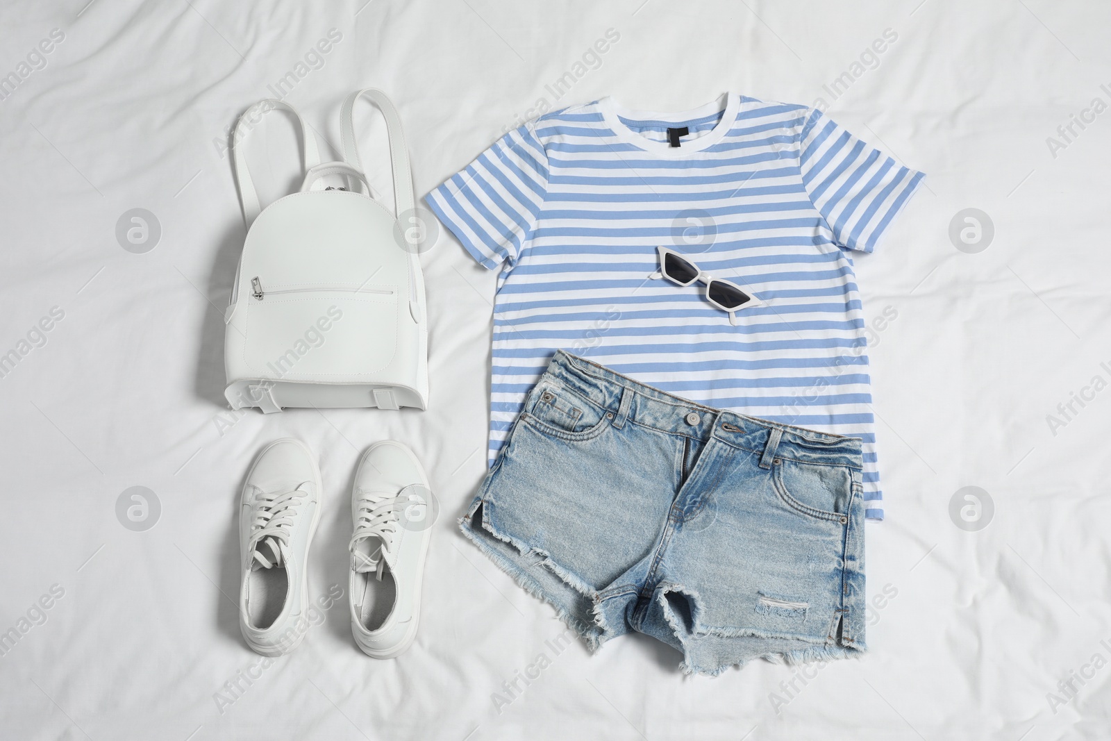 Photo of Stylish outfit with backpack on white fabric, flat lay