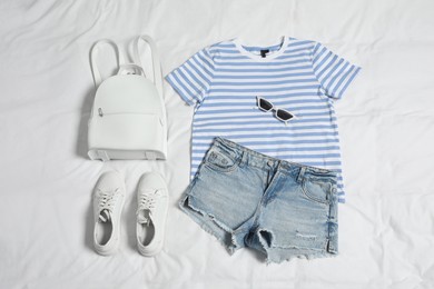 Photo of Stylish outfit with backpack on white fabric, flat lay