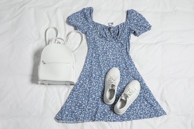 Photo of Stylish outfit with backpack on white fabric, flat lay