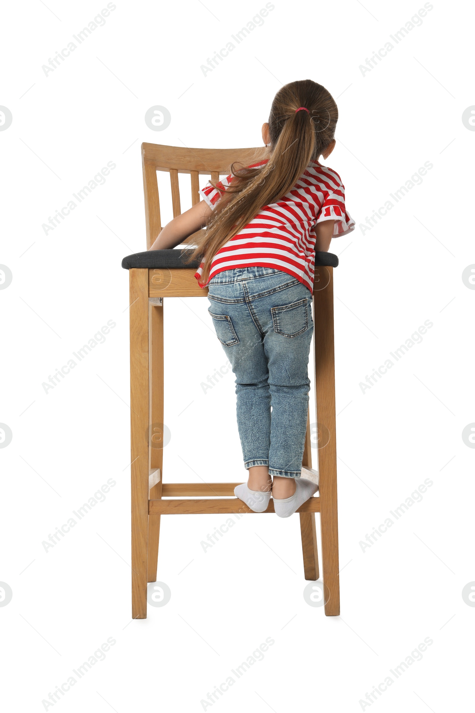 Photo of Little girl standing on stool against white background, back view