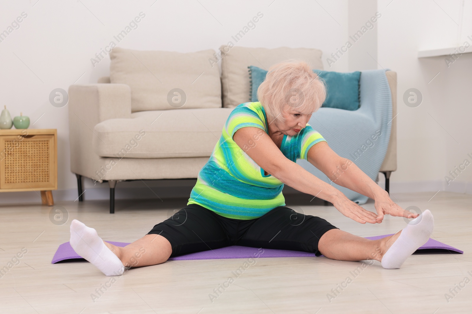 Photo of Senior woman exercising with fitness mat at home