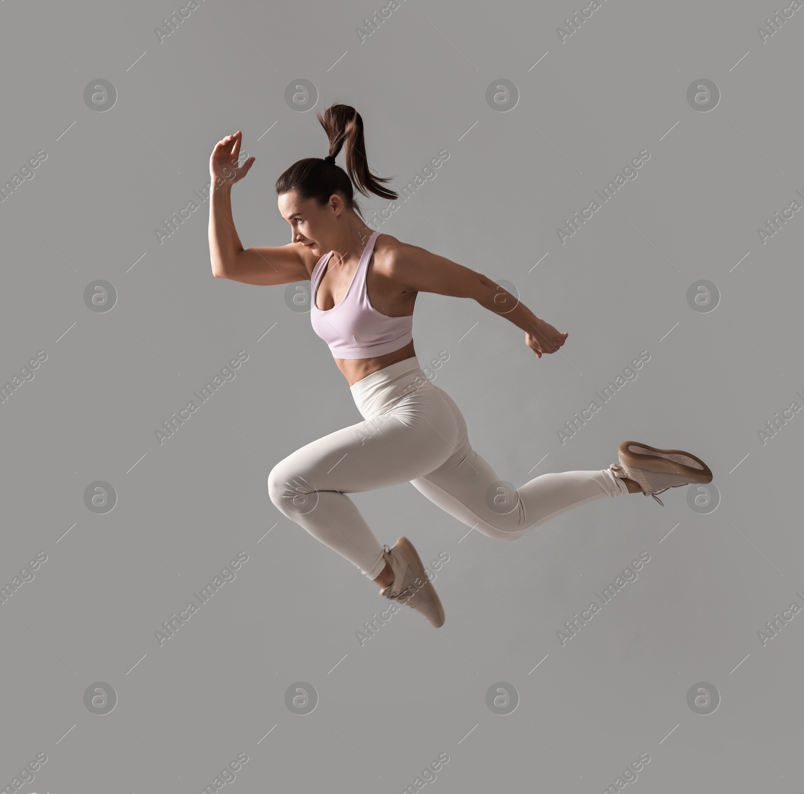 Photo of Woman in gym clothes doing exercise on grey background