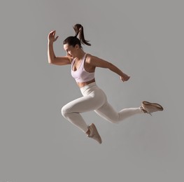 Photo of Woman in gym clothes doing exercise on grey background