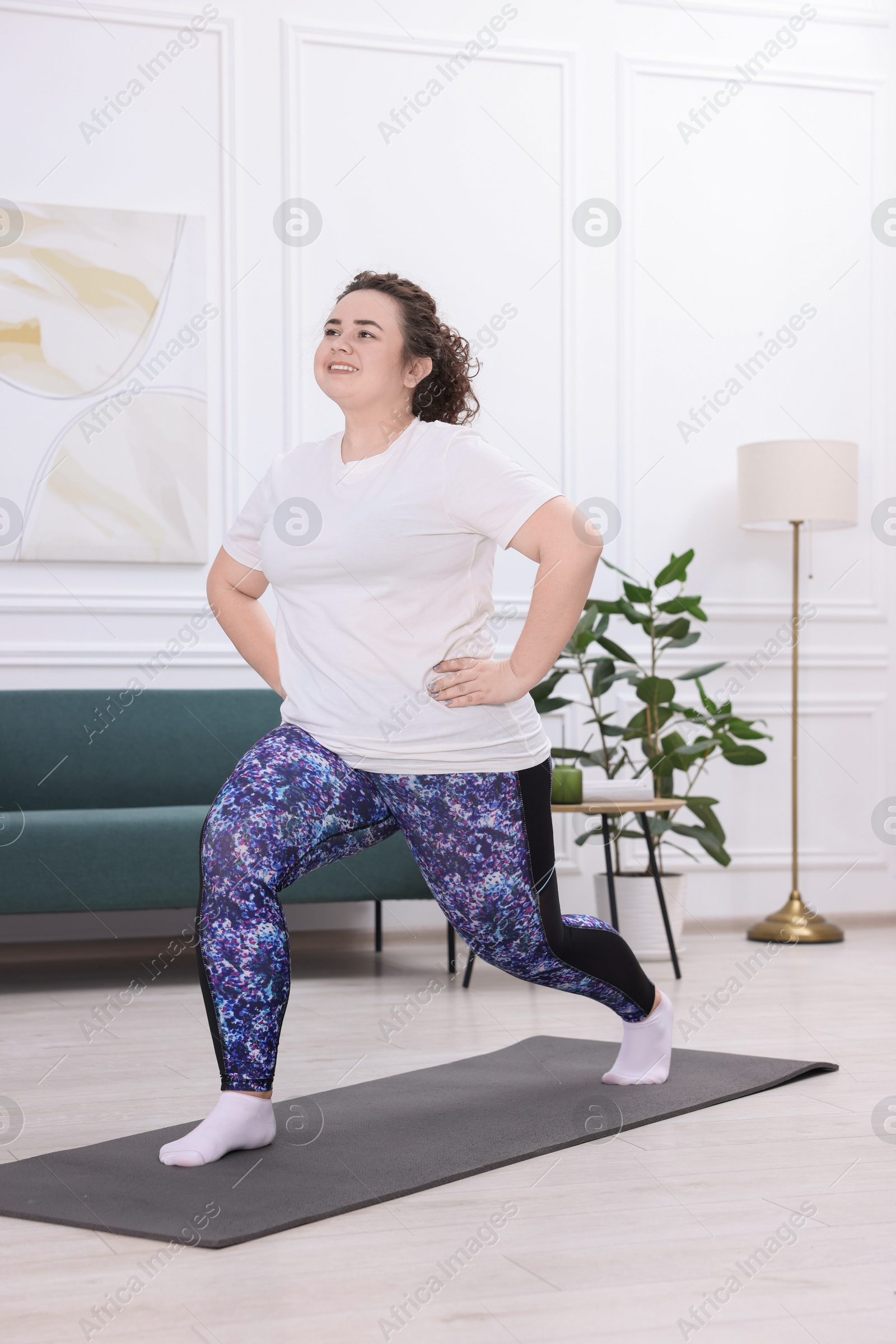 Photo of Plus size woman exercising on fitness mat at home