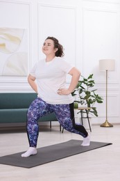 Photo of Plus size woman exercising on fitness mat at home