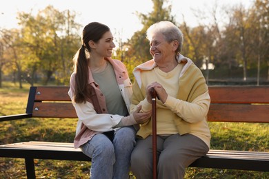 Photo of Elderly woman with walking cane and her caregiver in park