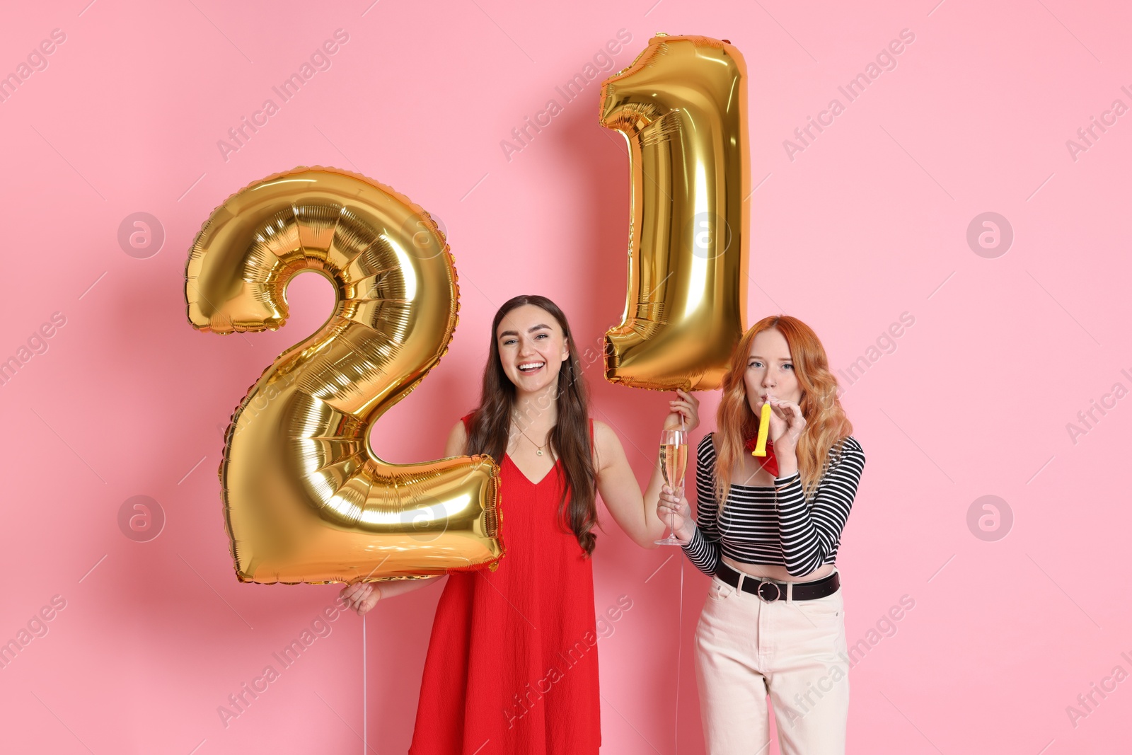 Photo of Coming of age party - 21st birthday. Young women celebrating with number shaped balloons on pink background