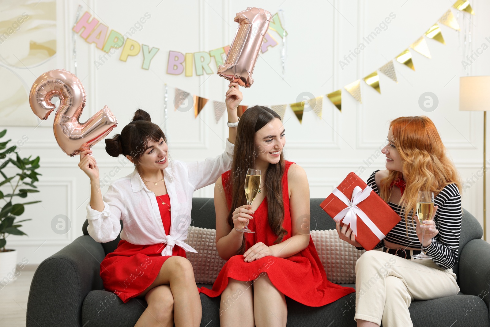 Photo of Coming of age party - 21st birthday. Group of young women celebrating with number shaped balloons at home