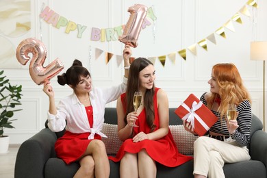 Photo of Coming of age party - 21st birthday. Group of young women celebrating with number shaped balloons at home