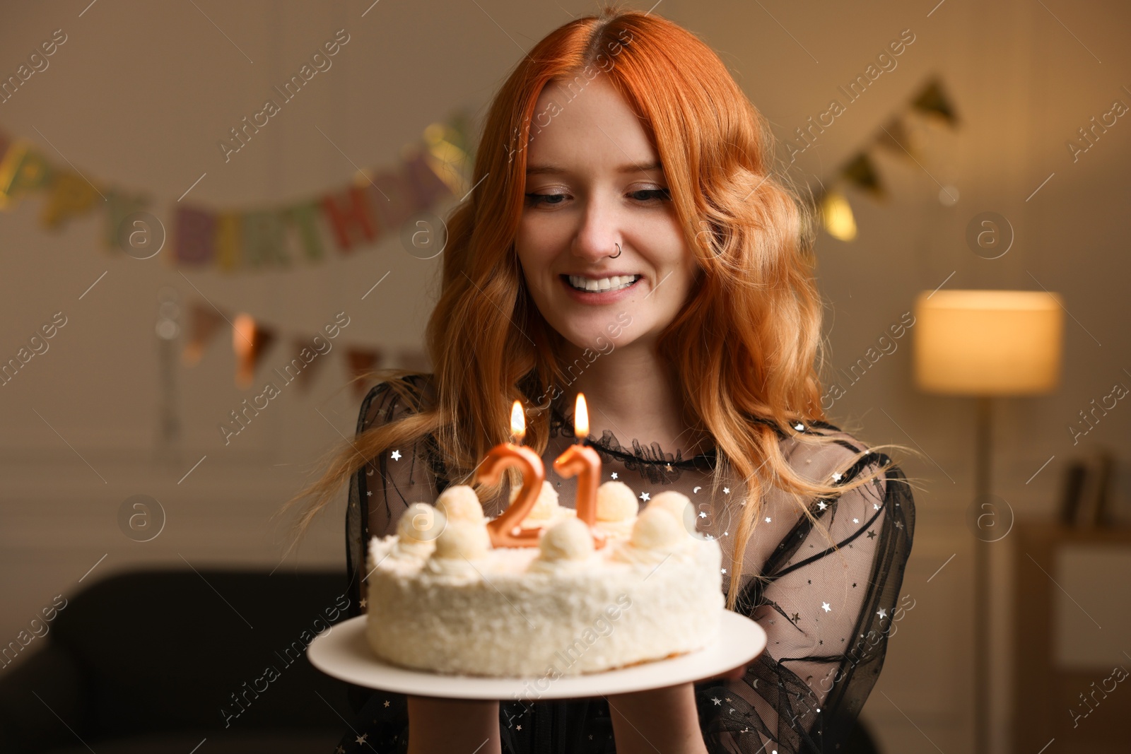 Photo of Coming of age party - 21st birthday. Happy young woman holding tasty cake with number shaped candles at home