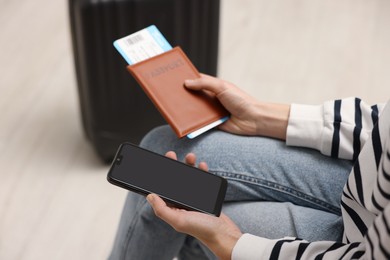 Photo of Traveller with passport, flight ticket and smartphone indoors, closeup