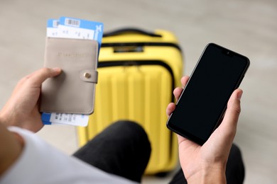 Photo of Traveller with passport, flight tickets and smartphone indoors, closeup