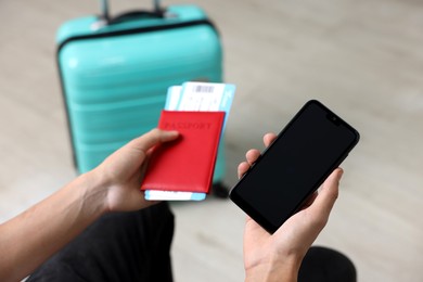 Photo of Traveller with passport, flight tickets and smartphone indoors, closeup