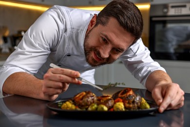 Photo of Professional chef serving dish at table indoors, selective focus