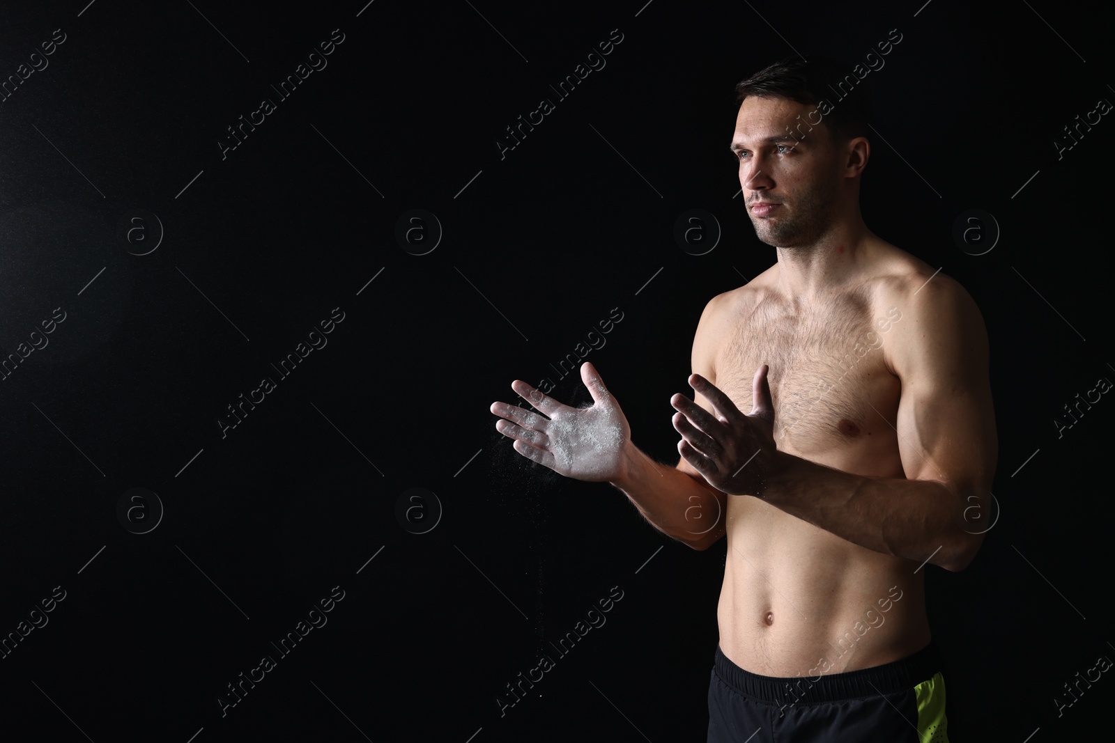 Photo of Man clapping hands with talcum powder before training on black background. Space for text