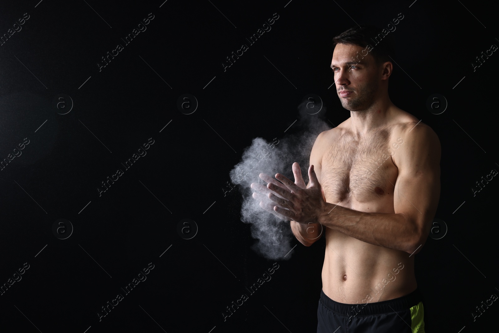 Photo of Man clapping hands with talcum powder before training on black background. Space for text