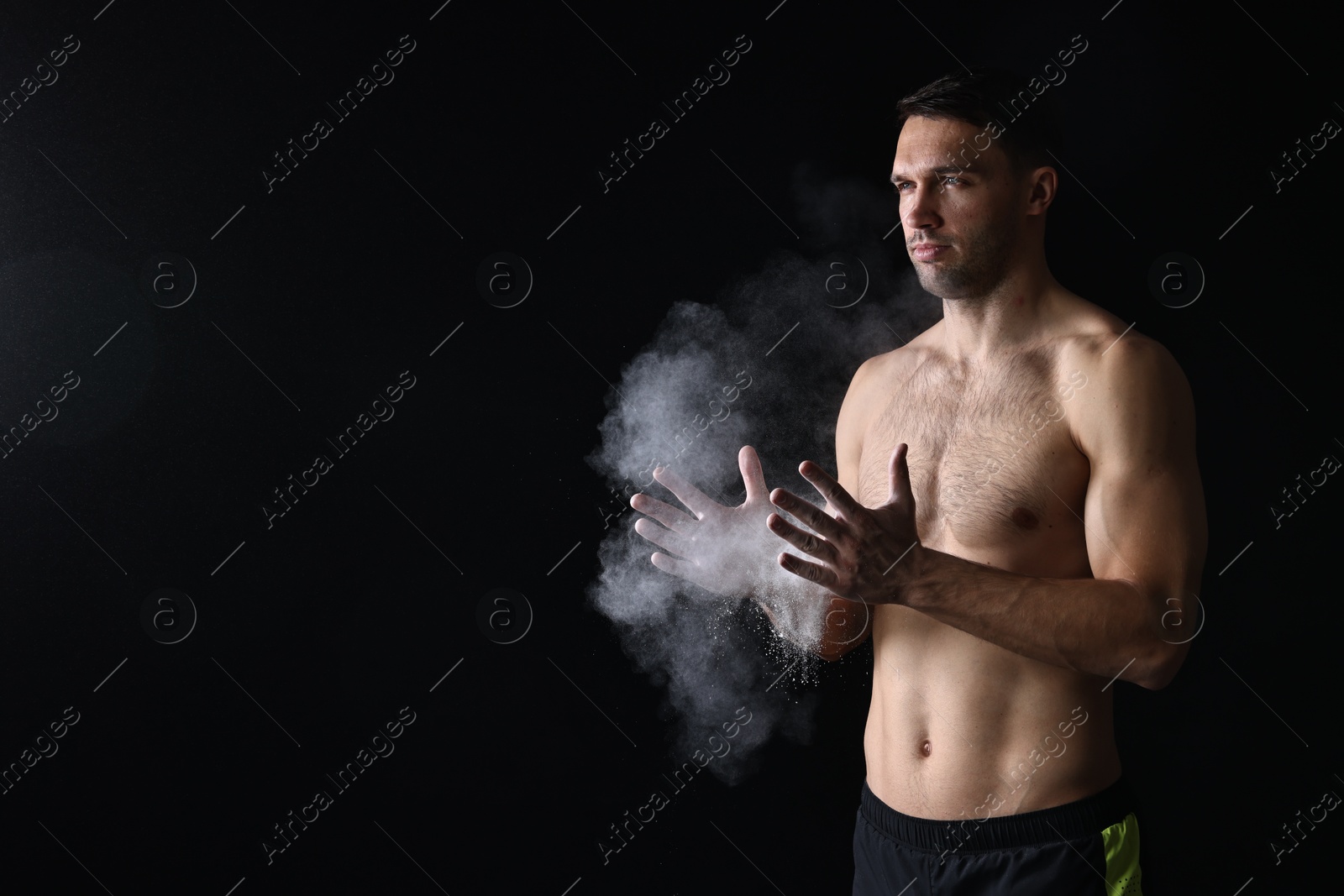 Photo of Man clapping hands with talcum powder before training on black background. Space for text