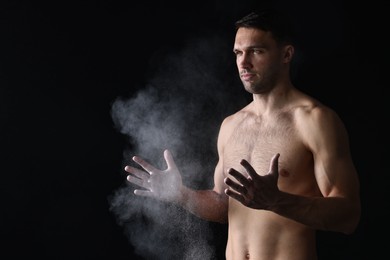 Photo of Man clapping hands with talcum powder before training on black background. Space for text