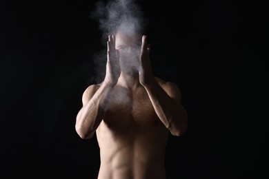 Photo of Man clapping hands with talcum powder before training on black background