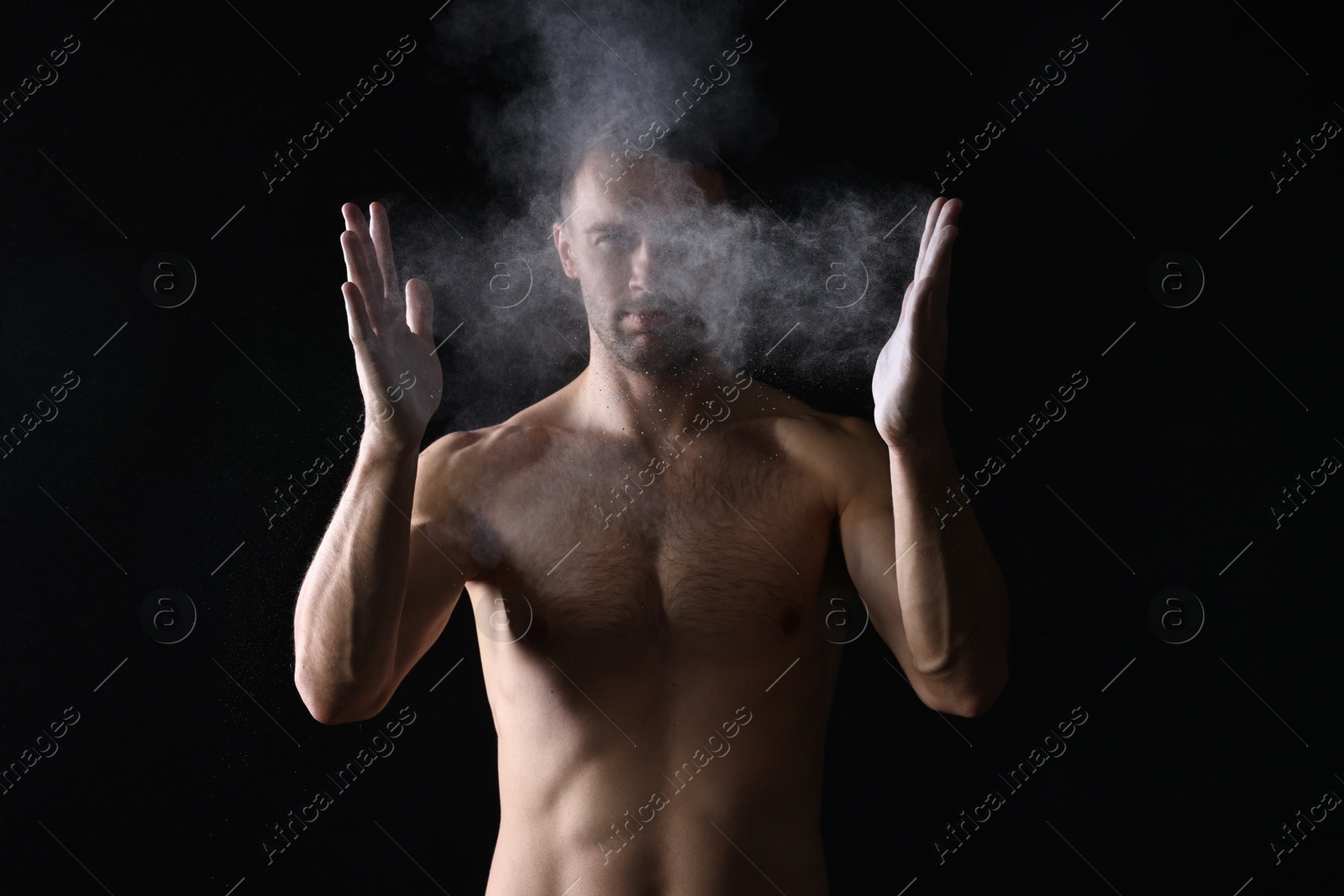 Photo of Man clapping hands with talcum powder before training on black background