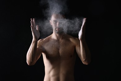 Photo of Man clapping hands with talcum powder before training on black background