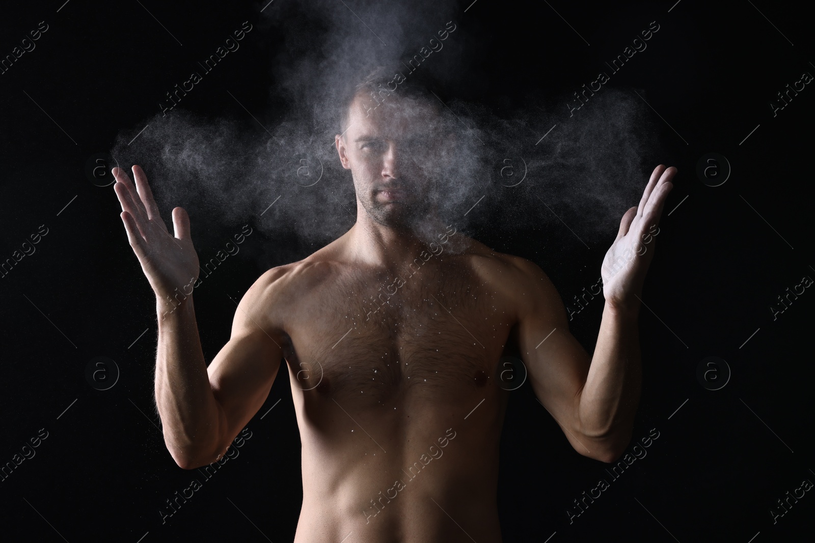 Photo of Man clapping hands with talcum powder before training on black background