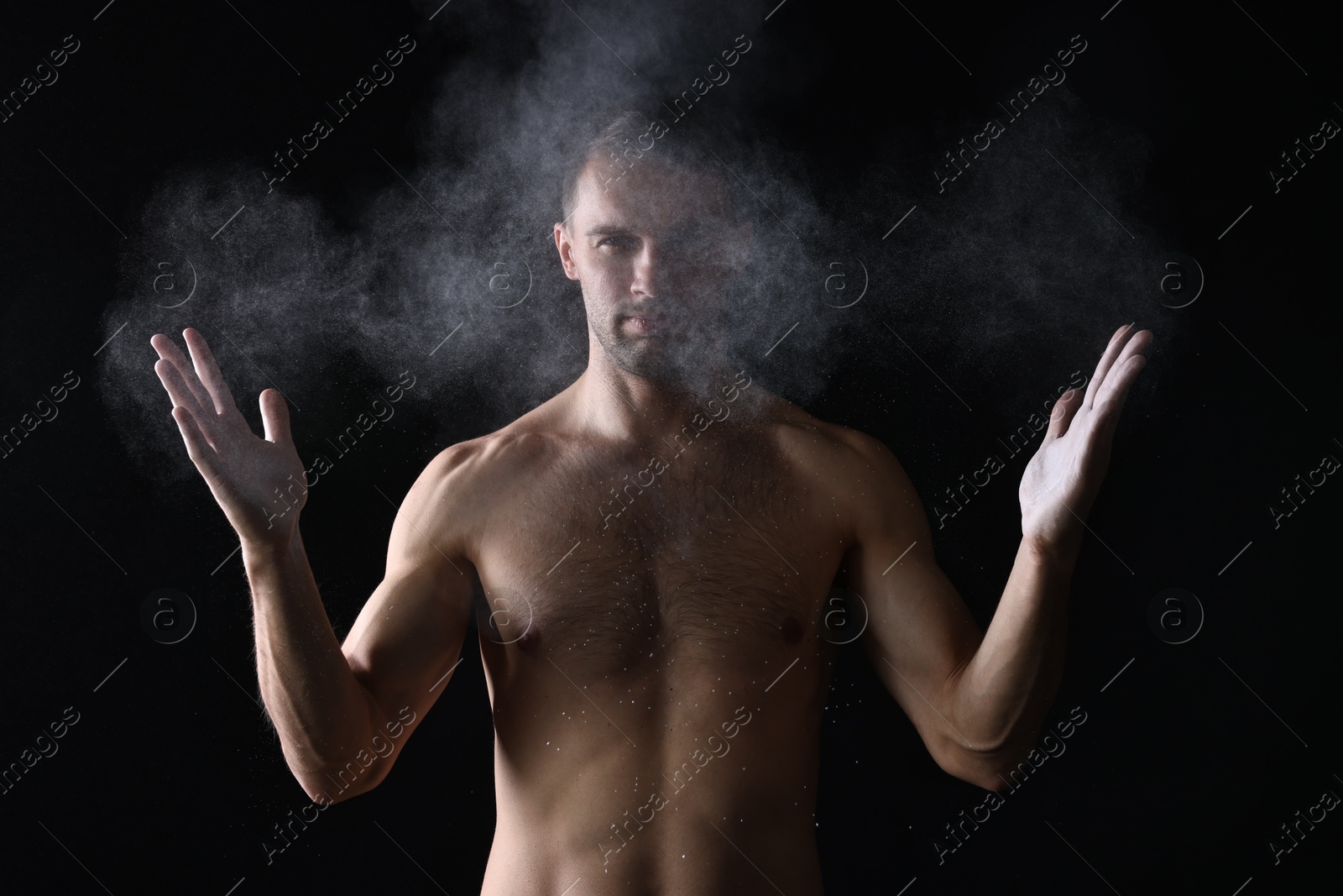 Photo of Man clapping hands with talcum powder before training on black background