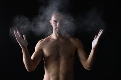 Photo of Man clapping hands with talcum powder before training on black background