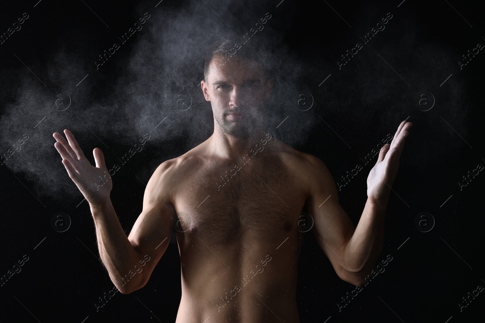 Photo of Man clapping hands with talcum powder before training on black background