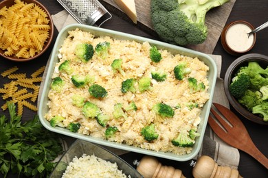 Photo of Uncooked pasta casserole in baking dish and ingredients on wooden table, flat lay