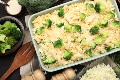 Photo of Uncooked pasta casserole in baking dish and ingredients on wooden table, flat lay