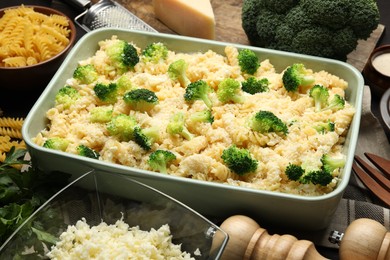 Photo of Uncooked pasta casserole in baking dish and ingredients on table, closeup