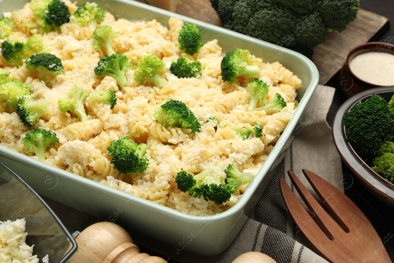 Photo of Uncooked pasta casserole in baking dish and ingredients on table, closeup