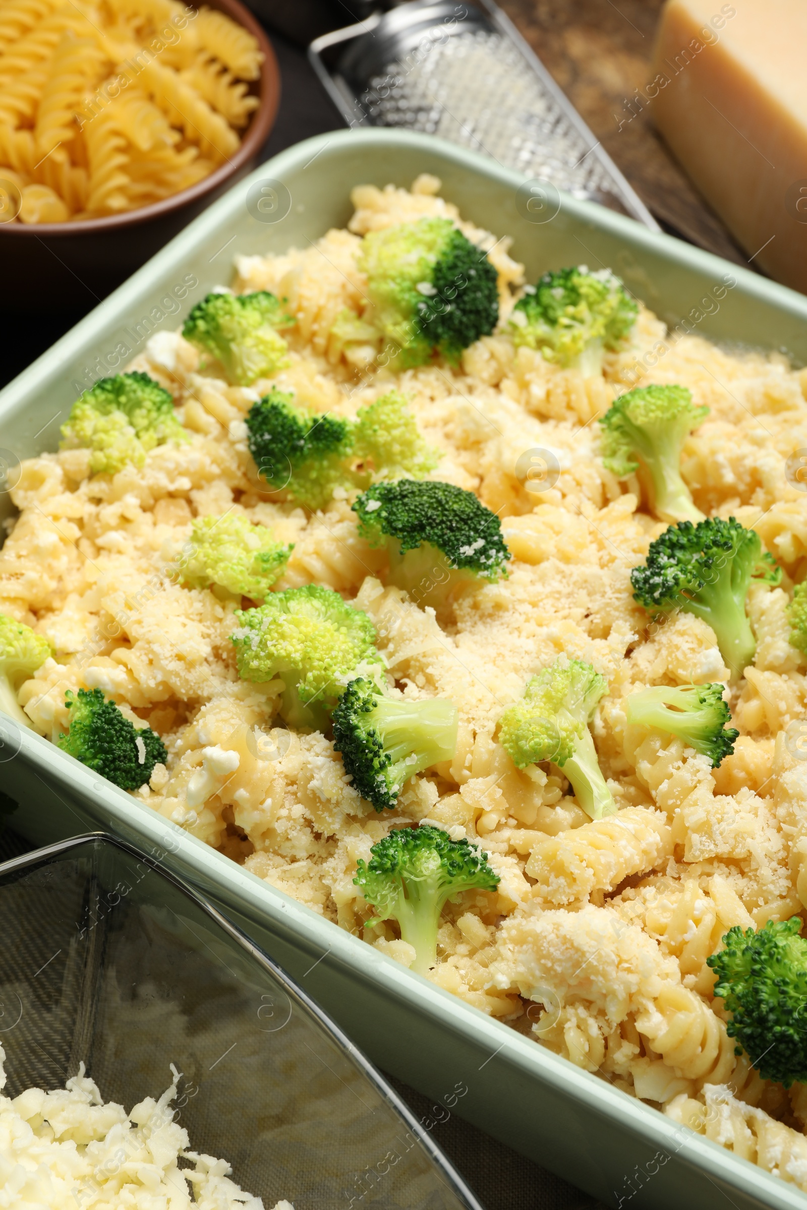 Photo of Uncooked pasta casserole in baking dish and ingredients on table, closeup