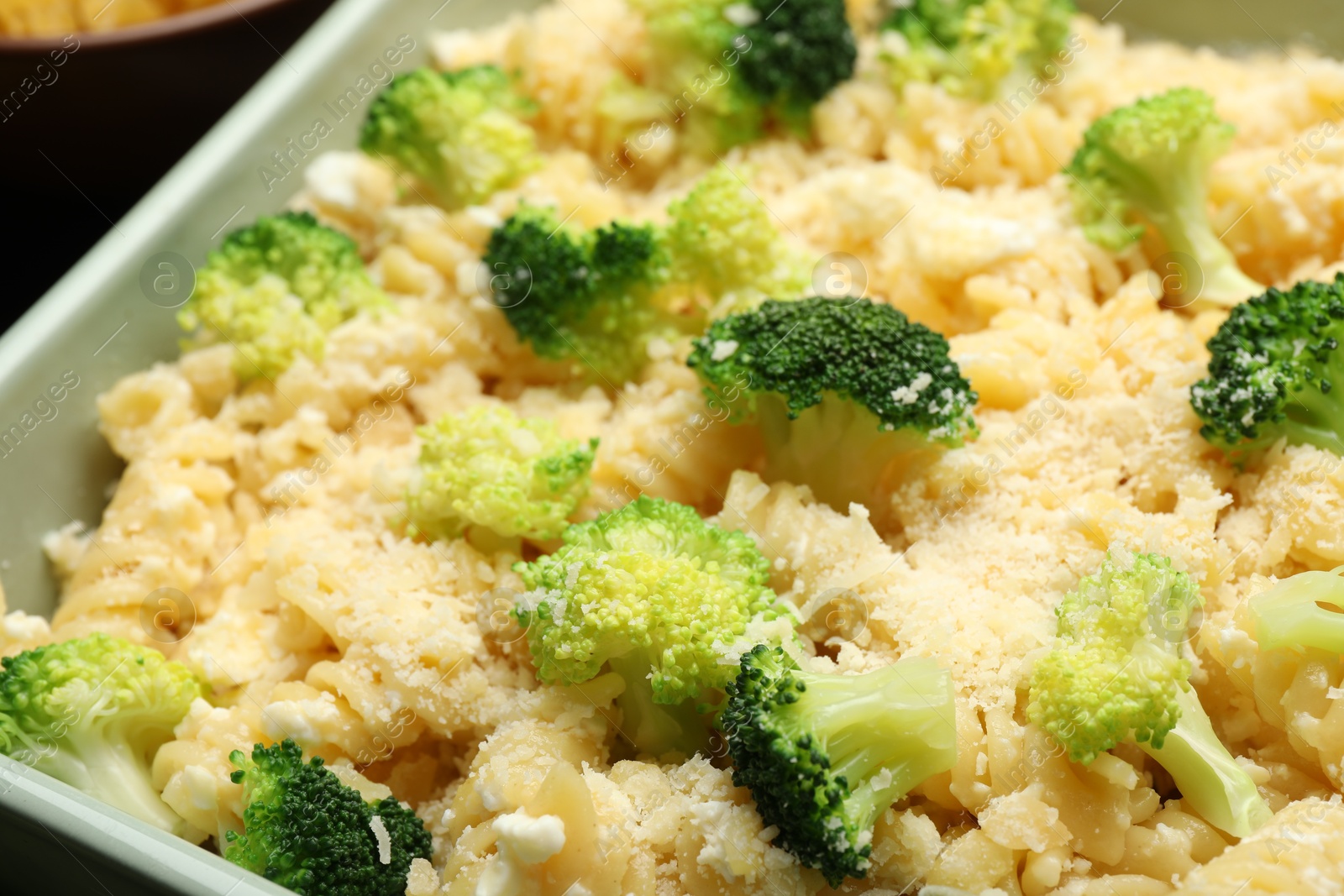 Photo of Uncooked pasta casserole with cheese and broccoli in baking dish on table, closeup