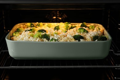 Photo of Baking dish with uncooked pasta casserole in oven, closeup