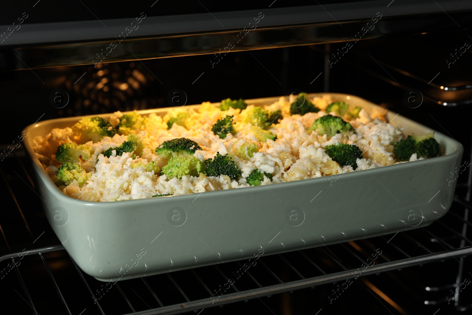 Photo of Baking dish with uncooked pasta casserole in oven, closeup