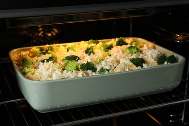 Photo of Baking dish with uncooked pasta casserole in oven, closeup