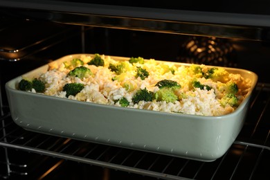 Photo of Baking dish with uncooked pasta casserole in oven, closeup